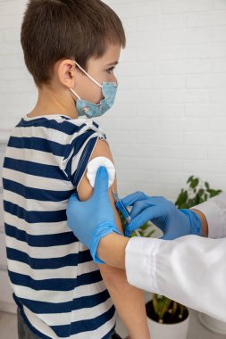 Aşı sırasında maske takan çocuk, doktorun muayenehanesinde iğne olan çocuk..