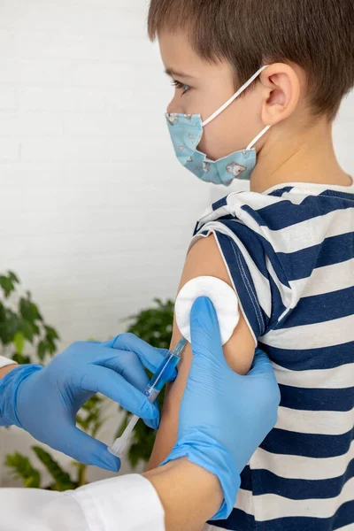 Aşı sırasında maske takan çocuk, doktorun muayenehanesinde iğne olan çocuk..