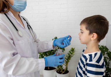 Doktor çocuğa vitamin jelibonu veriyor, çocuk doktoru sağlıklı besinler öneriyor..