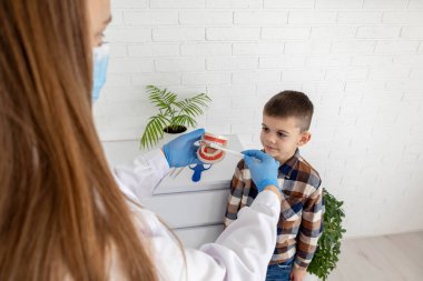 Diş hekimi, dişlerini nasıl fırçalayacağını gösteriyor..