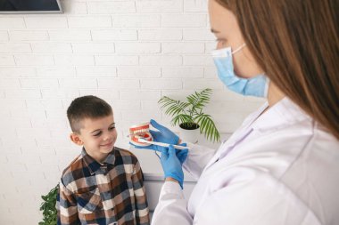 Diş hekimi, dişlerini nasıl fırçalayacağını gösteriyor..