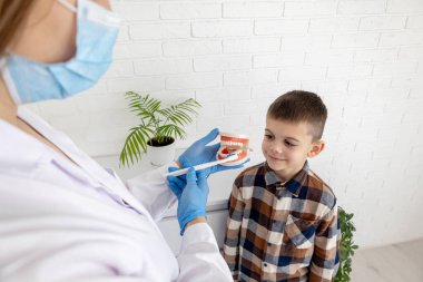 Diş hekimi, dişlerini nasıl fırçalayacağını gösteriyor..