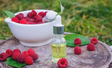 Şişe içinde ahududu esanslı yağ ve ahşap bir kütükte taze böğürtlen