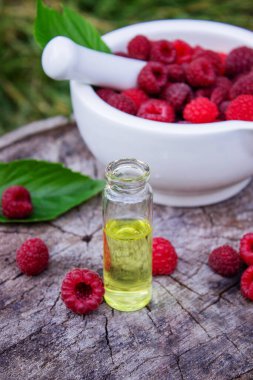 Şişe içinde ahududu esanslı yağ ve ahşap bir kütükte taze böğürtlen