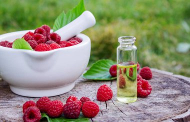 Şişe içinde ahududu esanslı yağ ve ahşap bir kütükte taze böğürtlen