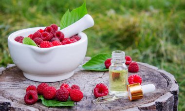 Şişe içinde ahududu esanslı yağ ve ahşap bir kütükte taze böğürtlen