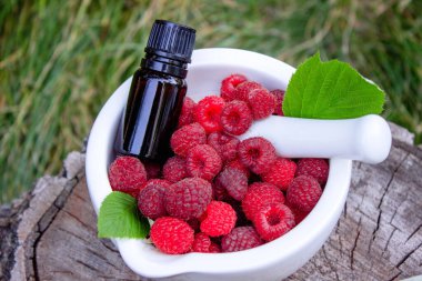 Şişe içinde ahududu esanslı yağ ve ahşap bir kütükte taze böğürtlen