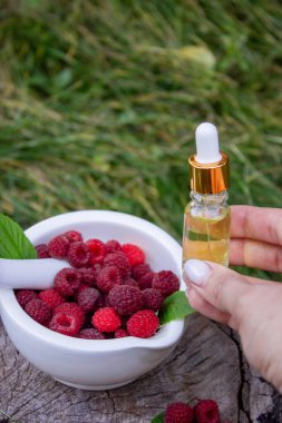 Şişe içinde ahududu esanslı yağ ve ahşap bir kütükte taze böğürtlen