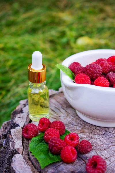 Şişe içinde ahududu esanslı yağ ve ahşap bir kütükte taze böğürtlen