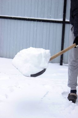 Siyah kürekle taze kar küremek, kışlık arazi bakımı