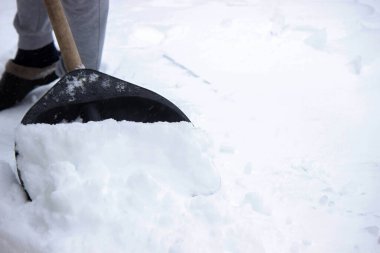Siyah kürekle taze kar küremek, kışlık arazi bakımı