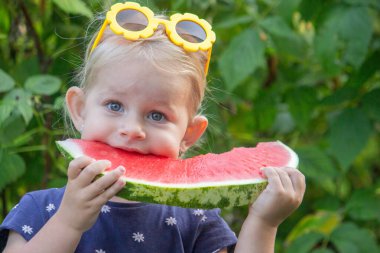 Büyük karpuz dilimli mutlu çocuk, yaz bahçesinde neşeli küçük kız.