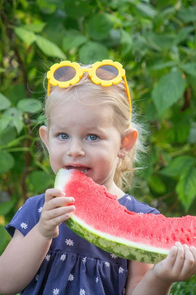 Büyük karpuz dilimli mutlu çocuk, yaz bahçesinde neşeli küçük kız.