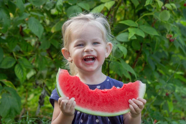 Büyük karpuz dilimli mutlu çocuk, yaz bahçesinde neşeli küçük kız.