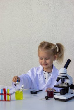 Laboratuvar önlüklü şirin küçük kız pipetle bilimsel deney yapıyor..