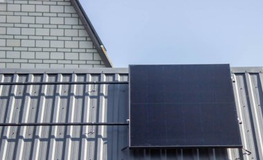 Güneş paneli mavi gökyüzünün altındaki özel bir evin metal çatısına kurulmuş..