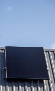 Güneş paneli mavi gökyüzünün altındaki özel bir evin metal çatısına kurulmuş..