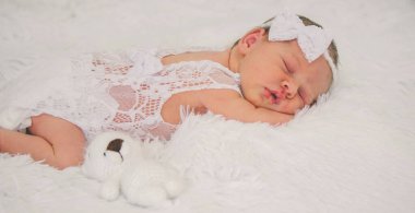 Yumuşak battaniyeli oyuncak ayıyla uyuyan yeni doğmuş bebek kız..