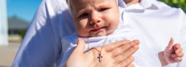 Bebeğin vaftiz töreni sırasında avuç içinde altın haç. Mutlu küçük kız. Vaftiz.