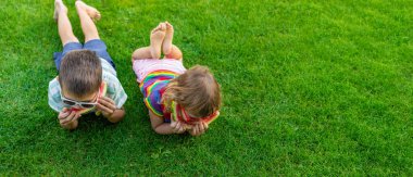 Güneş gözlüklü mutlu çocuklar yeşil çimlerde karpuz dilimleri yiyorlar..