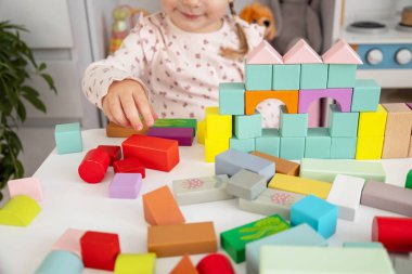 Evinde renkli tahta bloklar olan bir kale inşa eden küçük bir kız..