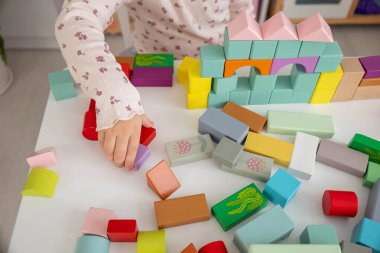 Evinde renkli tahta bloklar olan bir kale inşa eden küçük bir kız..