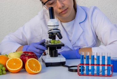 Bilim laboratuarında taze meyve kalitesini kontrol eden kadın bilim adamı..