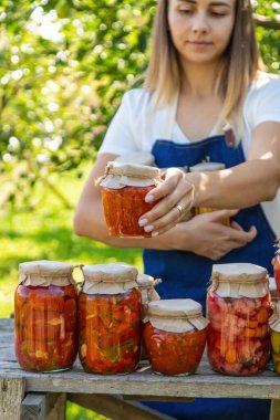 Güneşli bahçede ev yapımı domates kavanozu tutan kadın çiftçi..