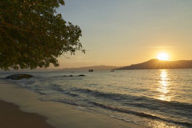 Altın ışık ve dramatik gökyüzü ile güzel bir gün batımı Atlantik Okyanusu sahilinde Santa Catarina Adası, Brezilya, Güney Amerika kıyıları boyunca dalgalarla birlikte
