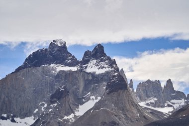 Güney Amerika 'da Güney Şili And Dağları' ndaki Torres del Paine Milli Parkı 'nda karla kaplı Torres del Paine boynuzları ve gökyüzünde dramatik bulutlar var.