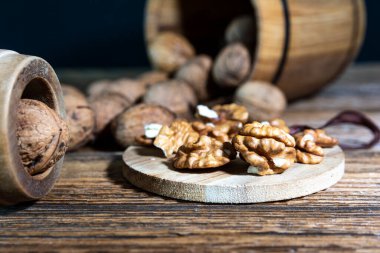 Tahta bir varilden eski bir tahtaya serpilmiş cevizler, ahşap bir tahtanın üzerinde soyulmuş fındıklar..
