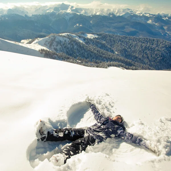 Gelukkige vrouw maken sneeuw engel in de sneeuw — Stockfoto