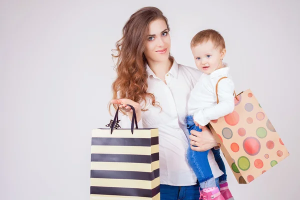 Matka i dziecko gospodarstwa torby z zakupów i zabawki — Zdjęcie stockowe