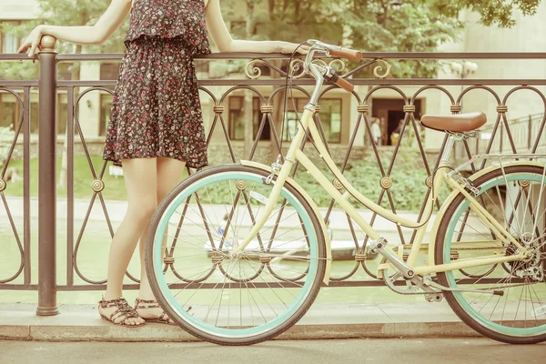 Chica joven de pie cerca de la cerca, cerca de la bicicleta de la ciudad vintage — Foto de Stock