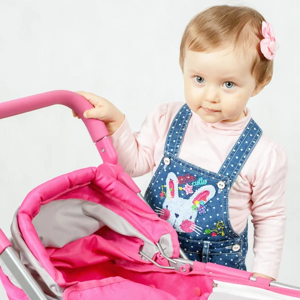 Cute little girl playing with baby stroller — Stock Photo, Image