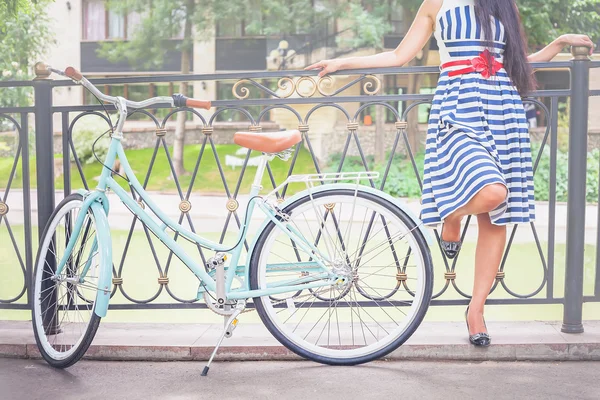 Junges Mädchen steht in der Nähe von Zaun neben Oldtimer-Fahrrad im Park — Stockfoto