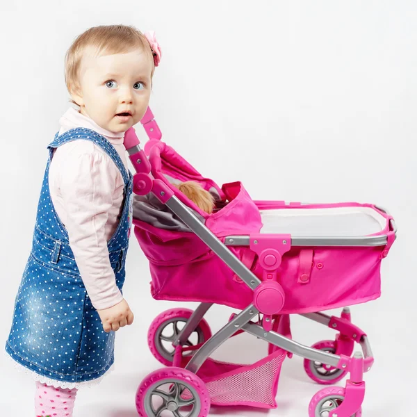 Cute little girl playing with baby stroller — Stock Photo, Image