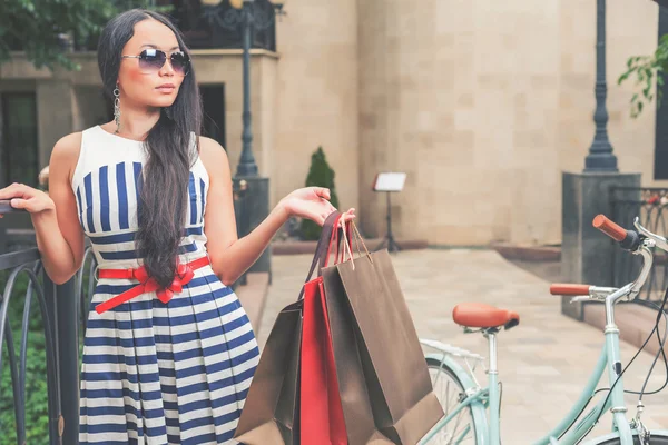 Fashion woman dressed in striped dress with bags — Stock Photo, Image