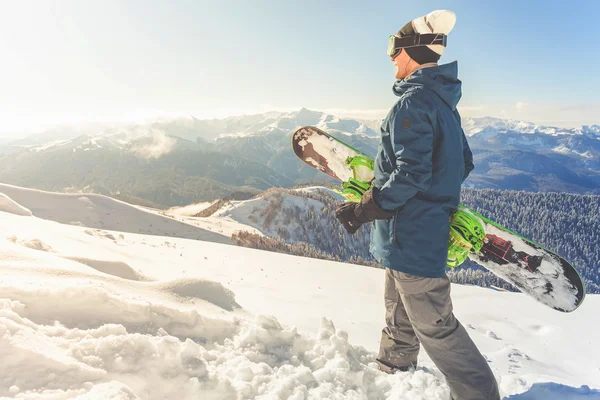 Avontuur aan wintersport. Snowboarder man wandelen op de berg — Stockfoto