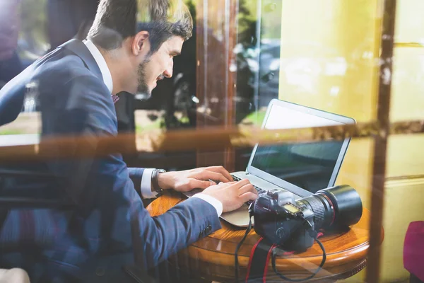 Young man photographer working at cafe, using laptop — Stock Photo, Image