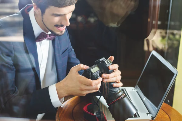 Jonge man fotograaf werken bij café, met behulp van de dslr camera — Stockfoto