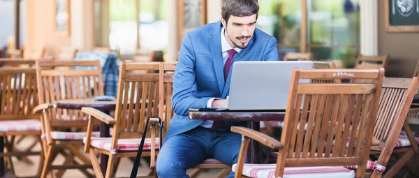 Przystojny człowiek za pomocą laptopa w chodniku kawiarnia na zewnątrz — Zdjęcie stockowe