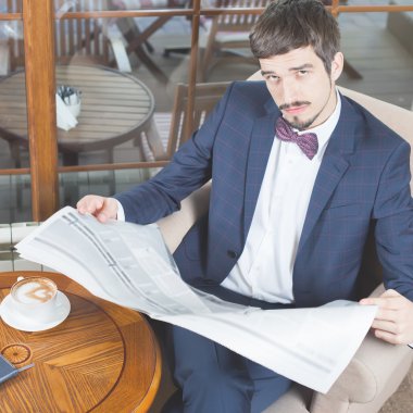 Kafede bir gazete okuyor, yas işadamı