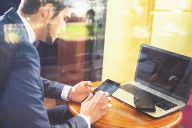 Cep telefonu kullaranarak café'de çalışan genç businesman