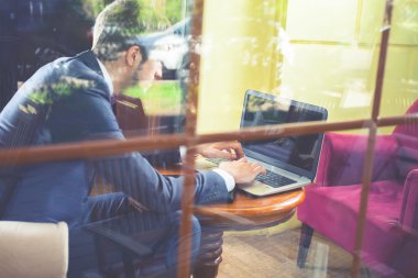 Genç businesman dizüstü bilgisayar kullanarak café'de çalışma