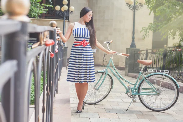 Ung flicka står nära stängslet nära vintage cykel på park — Stockfoto