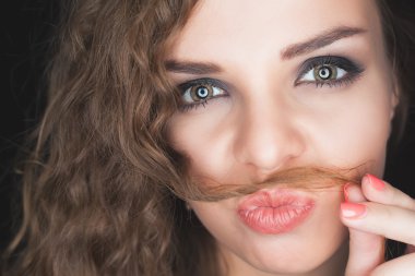 Young pretty girl making mustache of her hair