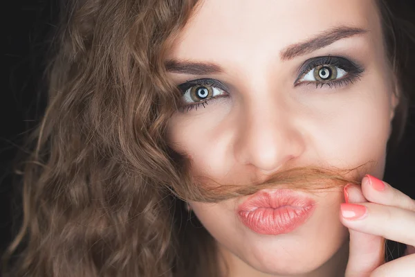 Young pretty girl making mustache of her hair