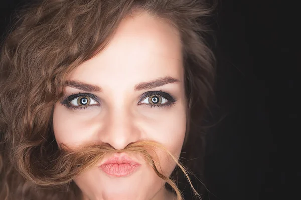 Menina bonita irritada fazendo bigode de seu cabelo — Fotografia de Stock