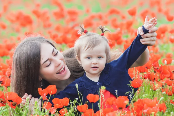 Mère avec drôle d'enfant en plein air au champ de fleurs de pavot — Photo